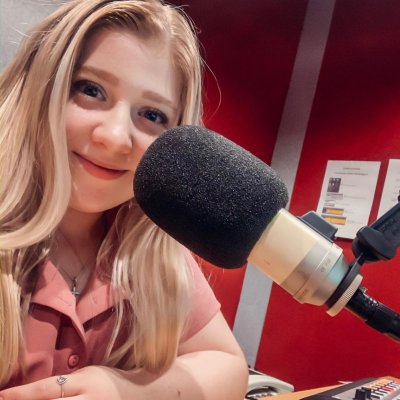 Woman sitting in front of a microphone smiling. 